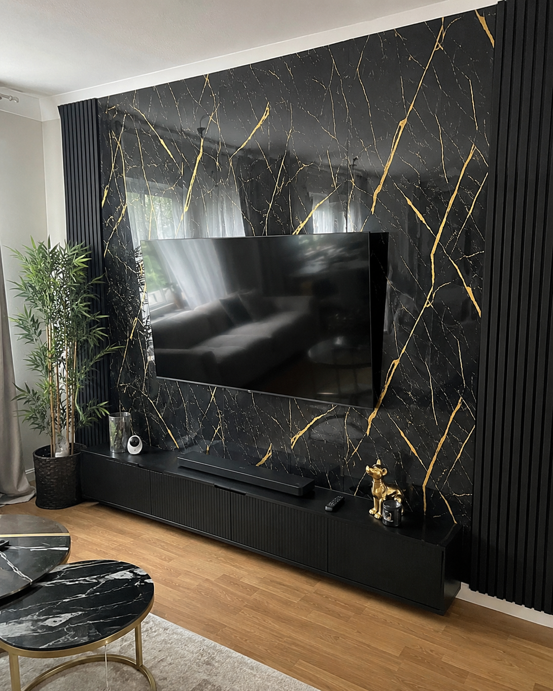 Schwarz-goldene Marmoroptik als TV-Wand im Wohnzimmer